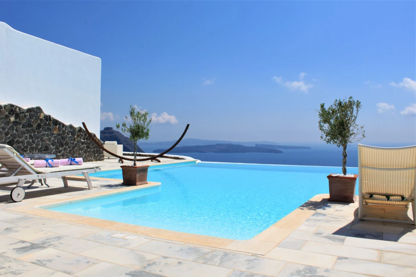 An infinity pool and sun loungers overlook the Aegean Sea in Santorini